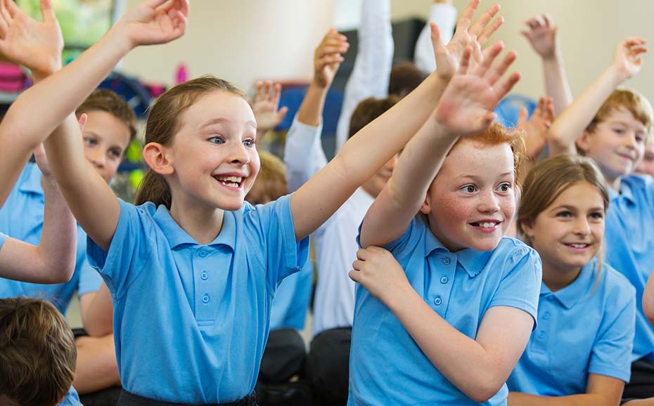 Excited primary school children with hands up