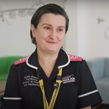Nursing apprentice Evolina seated in hospital uniform and lanyard