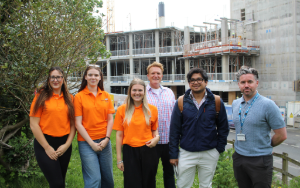 Students and lecturer and UHP partners group on grass outside hospital class=