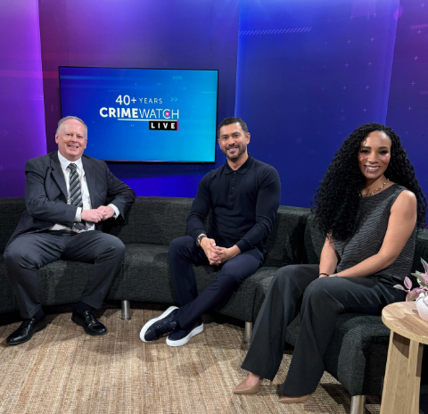 Crimewatch presenters on BBC couch with David Moore with blue/purple background