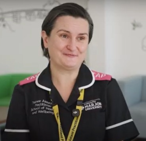 Nursing apprentice Evolina seated in hospital uniform and lanyard