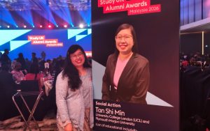 Photo of Shi Min at award ceremony alongside pull up banner of her award