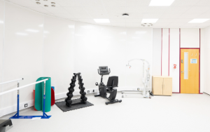 A gym in a clinic room with weights and exercise bike