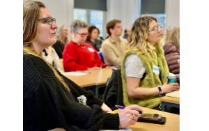 Two female students who are seated and listening intently to conference talks