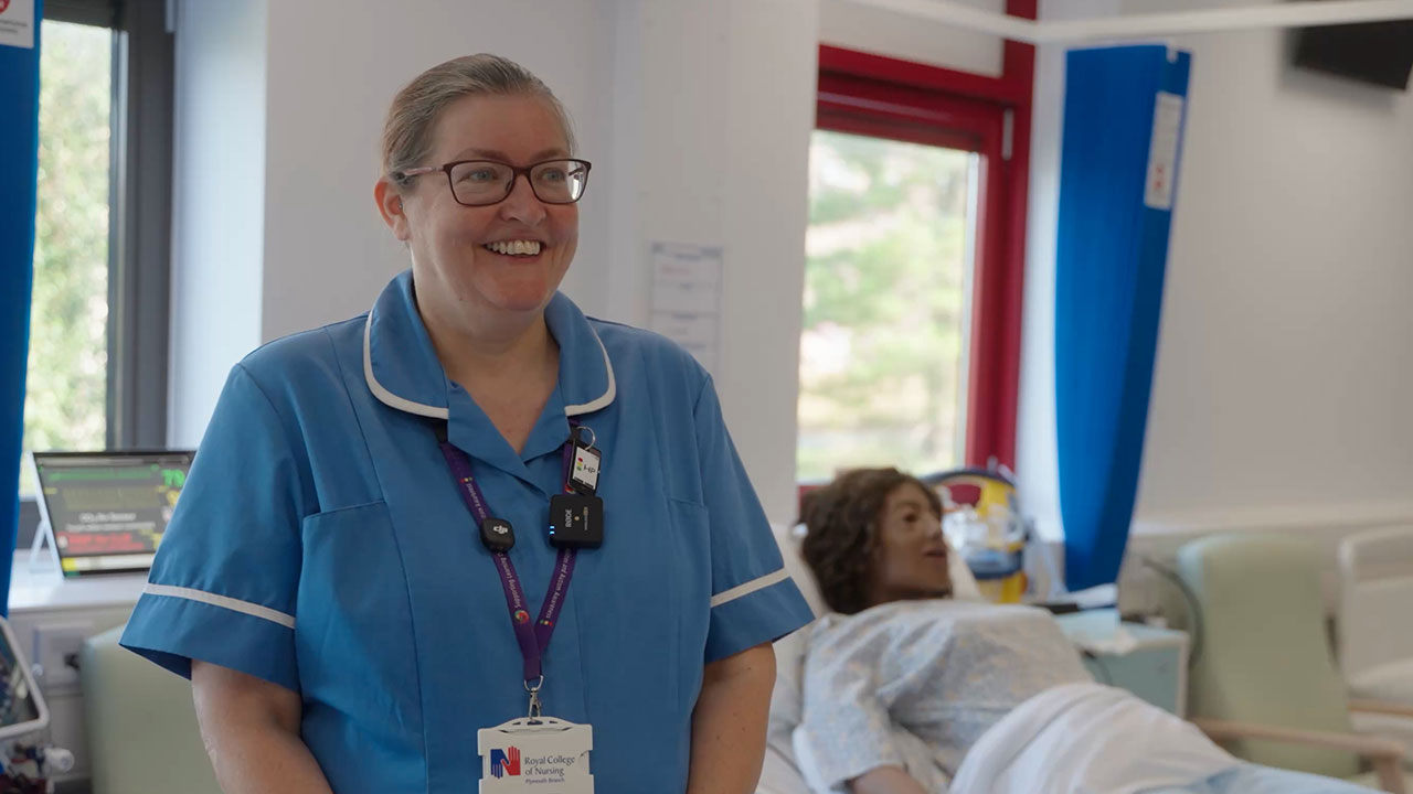 Smiling nurse in blue university standing in Marjon's simulation ward