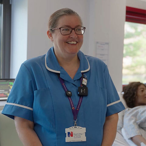 Smiling nurse in blue university standing in Marjon's simulation ward