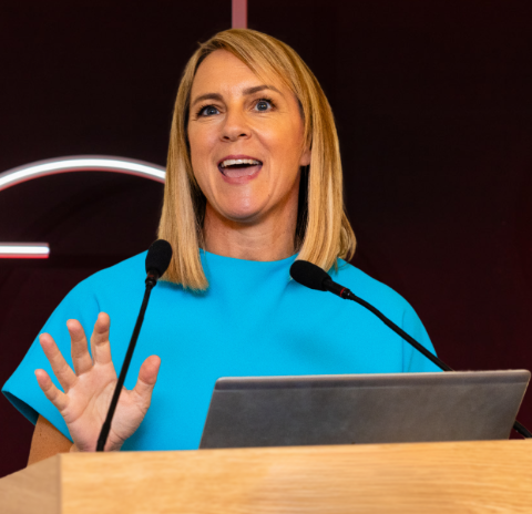 Smiling woman at lectern with microphones