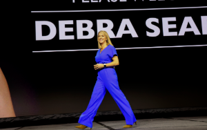 Smiling woman in blue suit walking across stage