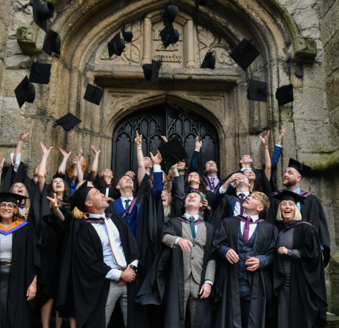 Group of graduating students throw hats in the air